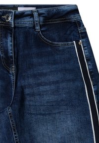 Donkerblauwe denim jeans met een klassieke pasvorm, subtiele vervaging, witte zijkanten en contrasterende stiksels in een gestructureerd ontwerp.