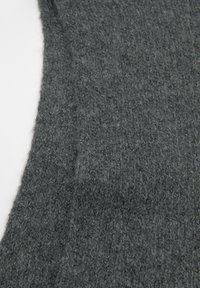 Mørkegrå strikket stof med en blød, struktureret overflade. Har en løs vævning og små variationer i fibertykkelsen.