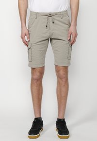Helle beige Cargo-Shorts mit einem Kordelzugbund, seitlichen Taschen und einer lockeren Passform. Hergestellt aus weichem Baumwollmaterial.