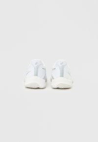 Paire de chaussures de course blanches avec semelles texturées et tissu en mesh, vues de dos sur un fond clair uni.