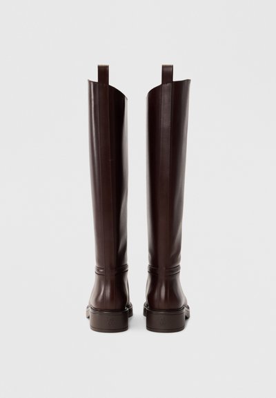 Bottes en cuir marron montant jusqu'au genou, avec une texture lisse, un design minimaliste et des languettes à l'arrière pour un enfilage facile. Bout carré et semelle robuste.