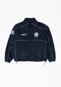 Černá sportovní bunda s bílým lemováním, zapínáním na zip, logy "USA 91" a "SPORT" a modrou záplatou na levém rukávu.