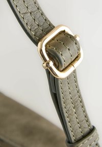 Bracelet en cuir vert texturé avec couture détaillée, sécurisé par une boucle carrée dorée.