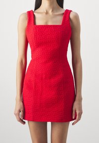 Punainen teksturoidusta kankaasta valmistettu mini mekko, jossa on neliönmuotoinen pääntie, tiukka muotoilu ja leveät hihnat, korostaen rakennetta.
