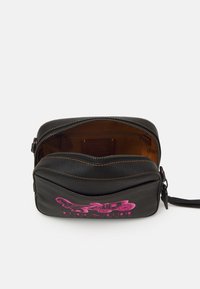 Schwarze Leder-Umhängetasche mit einem pinken Grafikdesign. Mit einem Reißverschlussverschluss und braunem Innenfutter. Kompakte Form mit kontrastierenden Nähten.