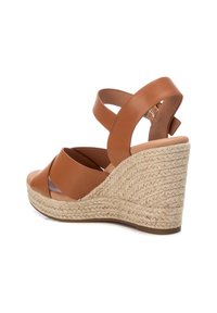 Sandalo con zeppa in pelle marrone con cinturini incrociati e tacco in juta intrecciata. La zeppa aggiunge altezza e presenta una finitura naturale e testurizzata.