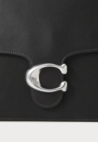 Borsa in pelle nera con una texture liscia, caratterizzata da una chiusura in logo argentato lucido e da cuciture bianche a contrasto lungo i bordi.