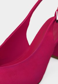 Escarpins slingback en daim rose vif avec bouts pointus et fines lanières sur fond blanc.