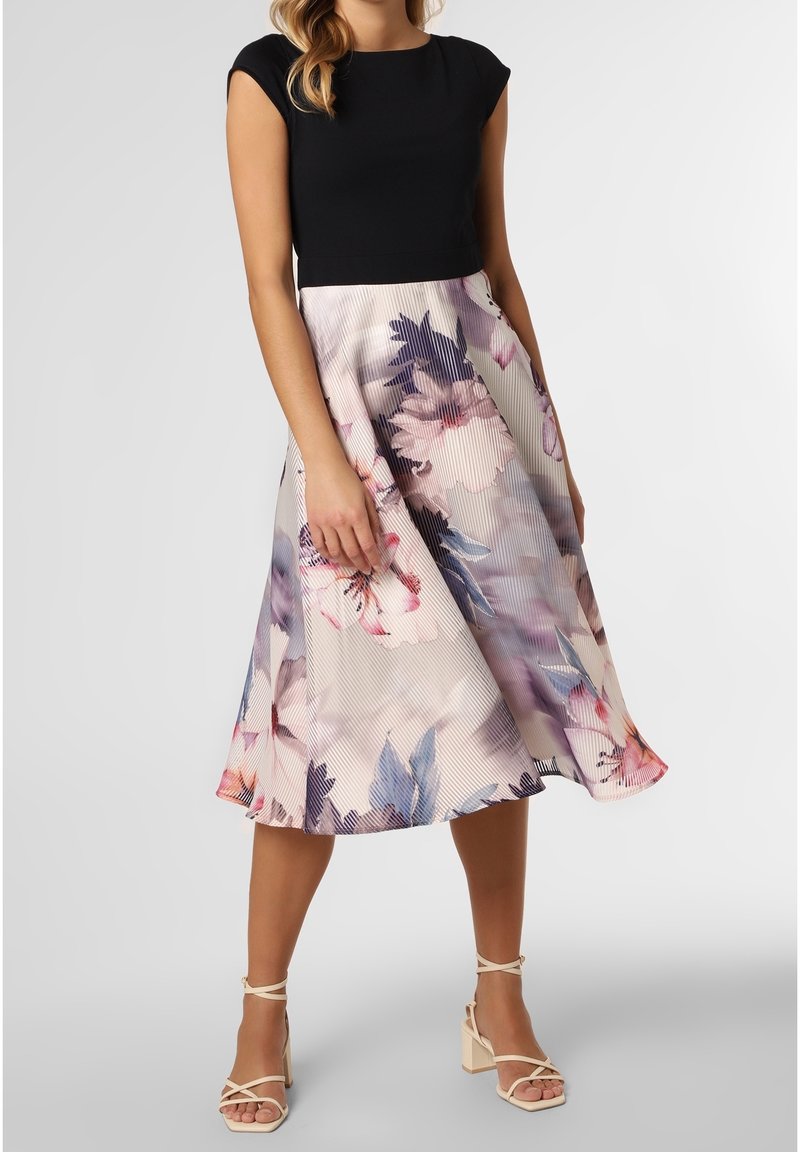 Robe fleurie avec un haut à manches courtes noires et une jupe plissée longueur genou présentant des motifs floraux roses et bleus sur un fond clair.