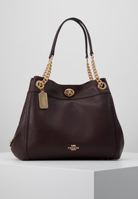 Ciemnobrązowa skórzana torebka o fakturowanym wykończeniu, z paskami łańcuchowymi w kolorze złota, wyrazistym zapięciem i oznakowaną metką. Pojemny, zaokrąglony fason.