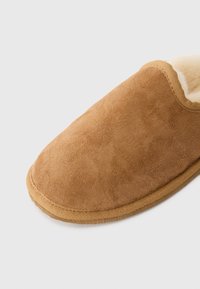 Καφέ σουέτ παντοφλέτα με μαλακή, υφή στην επιφάνεια και αφρώδη επένδυση. Στρογγυλή μύτη και καφέ καουτσούκ σόλα για άνεση.