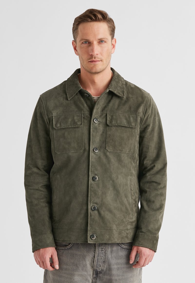 Olivgrüne Cordjacke mit Kragen, zwei Brusttaschen und Knopfverschluss. Weicher Stoff; funktionales Design, das sich gut zum Schichten eignet.
