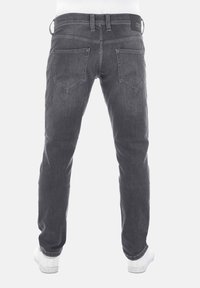 Jeans de mezclilla gris con corte recto, costuras visibles, bolsillos traseros y una etiqueta en la cintura negra. Llevados con zapatos blancos.