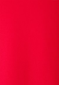 Jasnoczerwony materiał z teksturowaną powierzchnią, prezentujący jednolity wzór. Materiał wydaje się trwały i gładki, bez wyraźnych wariacji.