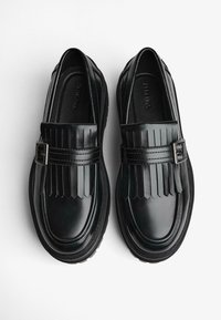 Fekete bőr loaferek frufrus dizájnnal, csattal és texturált talppal. Simább felület, kontrasztos matt és fényes részekkel.