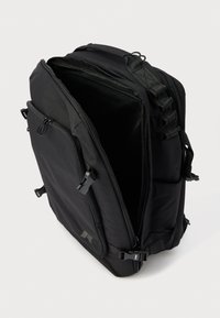 Melna mugursoma ar lielu galveno nodalījumu, vairākām rāvējslēdzēju kabatām un regulējamām siksnām. Iezīmējas ar izturīgu materiālu un elegantu, taisnstūrveida dizainu.