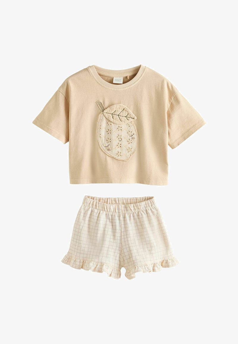 Beżowy krótki crop top z haftowanym wzorem cytryny i liścia, w połączeniu z jasnobeżowymi, kratkowymi szortami z elastycznym pasem i falbankowymi zakończeniami.