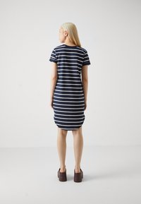 Rochie în dungi bleumarin cu mâneci scurte și tiv rotunjit, realizată dintr-un material moale. Designul are dungi albe alternante.