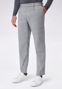 Pantaloni a quadri grigi con taglio dritto, davanti piatto, tasche laterali e passanti per cintura. Abbinati a sneakers bianche. Tessuto di texture liscia.