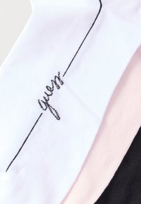 Tres calcetines en blanco, rosa y negro. El calcetín blanco presenta texto bordado en negro que dice "queen" con una línea decorativa encima.