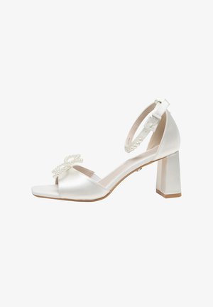 Weiße Satin-Sandalette mit Absatz, Knöchelriemen und Perlen-Schleifendetail am Vorderriemen, offenem Zehenbereich und Blockabsatz.