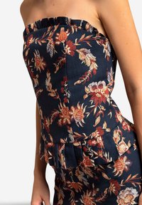 Strapless donkerblauwe jurk met oranje en beige bloemmotief, voorzien van een gerimpelde bovenrand en een peplum taille detail.