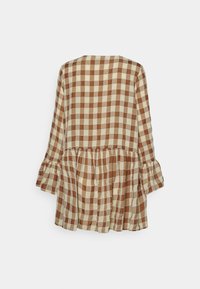 Brun och beige rutig blus med långa ärmar, volangkant och utsvängda ärmslut. Tillverkad av lätt tyg med mjuk textur.