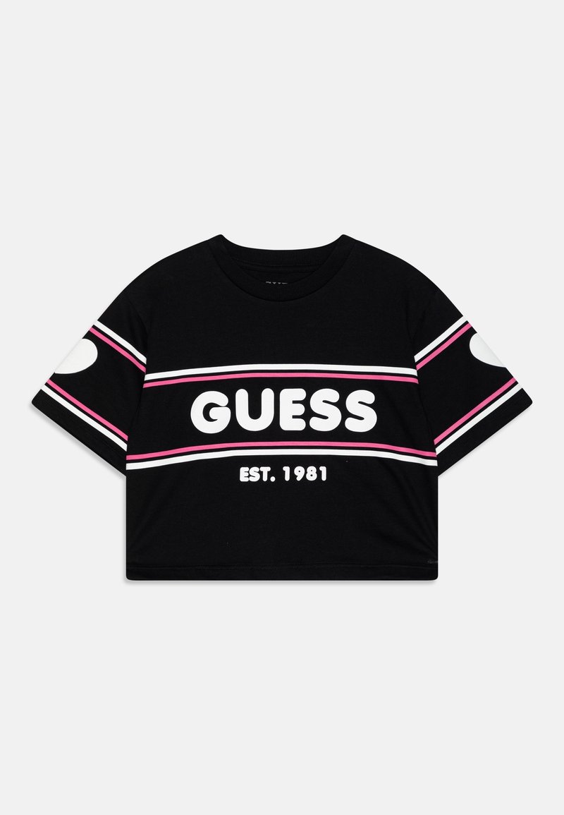 T-shirt court noir avec des rayures blanches et roses, grand texte blanc "GUESS", et "EST. 1981" en dessous à l'avant.