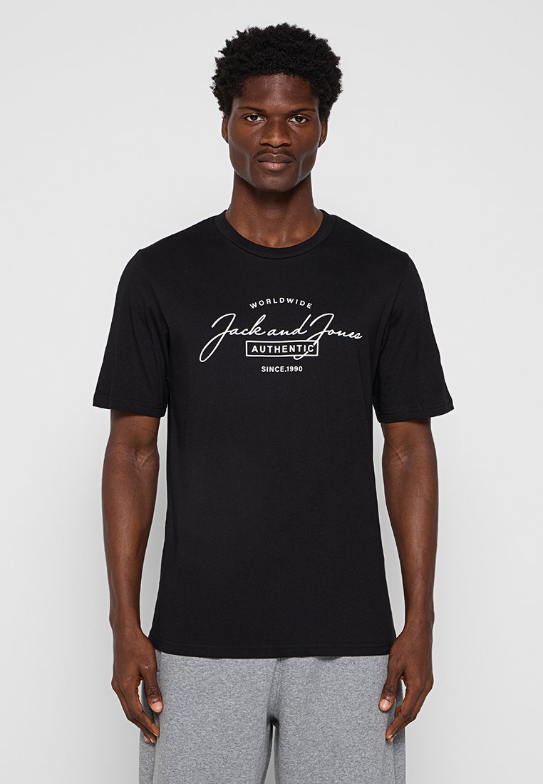 Schwarzes T-Shirt mit kurzen Ärmeln aus Baumwolle, versehen mit weißem Markentext "Jack and Jones" und der Jahreszahl "Seit 1990", die auf der Vorderseite gedruckt ist.