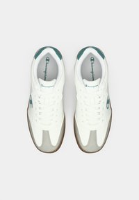 Hvite sneakers med teal-detaljer, overdel i lær og tekstil, avrundet tå, gummisåle, og fremtredende logo på siden og tungen.