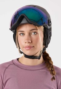 Black ski helmet with a textured surface, rainbow-tinted visor, and adjustable straps. Worn by a person in a light purple top.