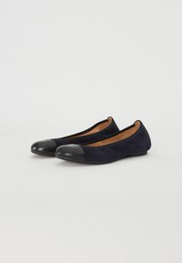 Ballerines en suede marine avec un capuchon en cuir noir, au design minimaliste et à la forme épurée. Légères avec une semelle basse pour plus de confort.