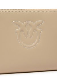 Bež kožna torbica s urezanim uzorkom, s bijelim šavom i glatkom teksturom. Zatvaranje na zip je smješteno na vrhu.