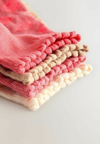 Vikta bomullssockor i olika nyanser av rosa och beige, med ribbade muddar och slät textur. Visas i en staplad uppställning.