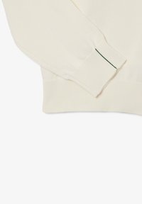 Maglione lavorato a maglia color crema con polsini e orlo a coste, arricchito da cuciture verdi sui polsini. Texture morbida e design casual.