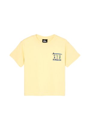 T-shirt jaune clair à manches courtes avec un petit dessin animé de trois personnes tenant une planche de surf et le logo Quiksilver sur la poitrine gauche.