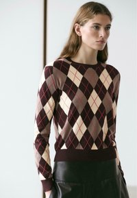 Pullover mit argyle-Muster in Burgunderrot, Creme und Beige, mit langen Ärmeln und rundem Ausschnitt, gefertigt aus weichem, strukturiertem Strickstoff.