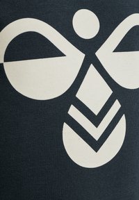 Navyblått tyg med en stor vit grafik, inklusive abstrakta former: en cirkel, en figur och zickzackmönster, som betonar textur och design.