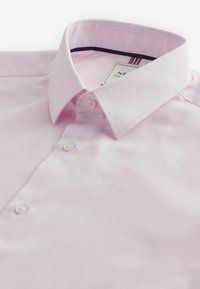 Camicia da uomo a maniche lunghe di colore rosa chiaro con colletto appuntito e tre bottoni bianchi visibili sul davanti.