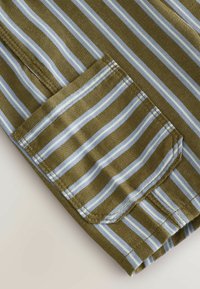 Olivgrüner Stoff mit hellblauen und weißen vertikalen Streifen, der eine kleine aufgenähte Tasche aufweist.