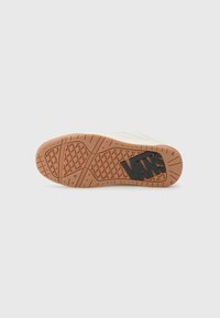 Vans sneaker sole featuring a brown rubber base with a textured grip pattern and a large black "VANS" logo embossed on the side.