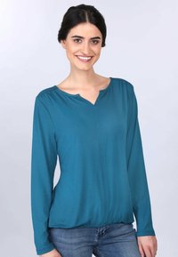 Türkisfarbige Bluse mit langen Ärmeln und V-Ausschnitt, gerafften Schulterdetails und einer leicht taillierten Taille. Glattes Material mit weicher Textur.