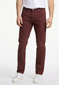 Bordeaux katoenen broeken met een slim fit, vijf zakken ontwerp en subtiele stikdetails. Gecombineerd met witte sneakers voor contrast.