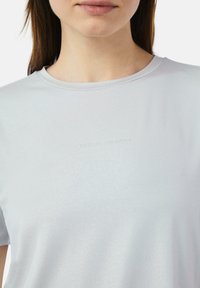 Jasnoszara koszulka krótki rękaw z gładkiego, lekko błyszczącego materiału. Posiada okrągły dekolt oraz wytłoczone logo "CASUAL IDENTITY".