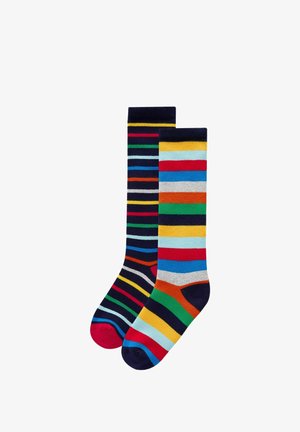 Chaussettes en coton rayées arborant des couleurs vives telles que le bleu, le rouge, le vert et le jaune. Chaque chaussette présente un motif et une forme uniques.