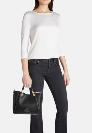 Borsa a mano in pelle nera con hardware dorato, caratterizzata da una superficie testurizzata e un design compatto e strutturato, tenuta da una persona in abbigliamento casual.