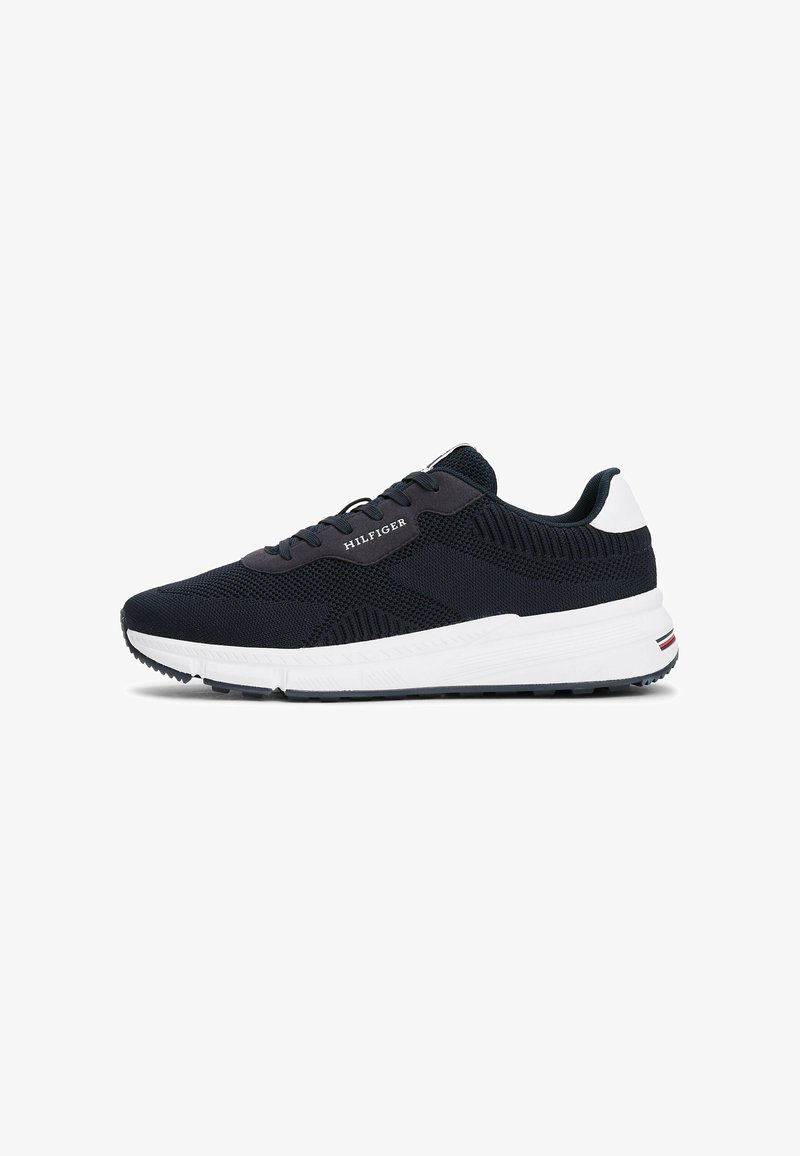 Marinekleurige sport sneakers met een mesh bovenkant, textuuraccenten, witte zool, zwarte rubberen zool en "HILFIGER" branding aan de zijkant.