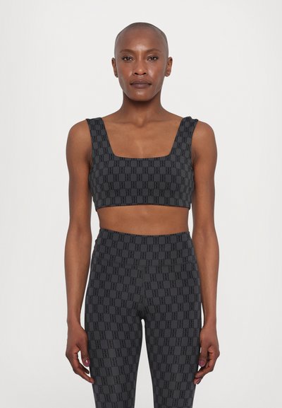 Μαύρο σετ με crop top και κολάν με γεωμετρικό σχέδιο. Το υλικό είναι ελαστικό, με τετράγωνα ντεκολτέ και φαρδιά λουριά.