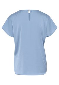 Blusa leggera azzurro chiaro a maniche corte con scollatura tonda e apertura a chiave sul retro fissata da un bottone metallico. Tessuto morbido, vestibilità rilassata.