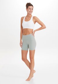 Ljusgrå sport-BH och matchande högmidjade shorts, tillverkade av elastiskt material, med en slät yta och minimala sömdetaljer.